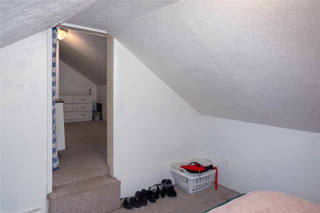 carpeted bedroom featuring a textured ceiling and vaulted ceiling