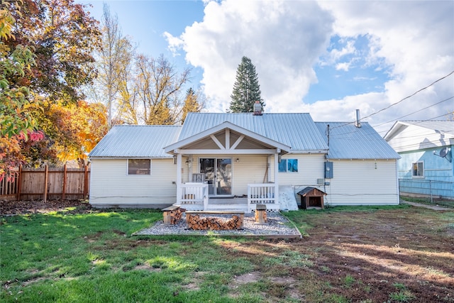 back of property with a lawn and a porch