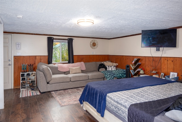 bedroom featuring crown molding, a textured ceiling, wooden walls, and dark hardwood / wood-style flooring