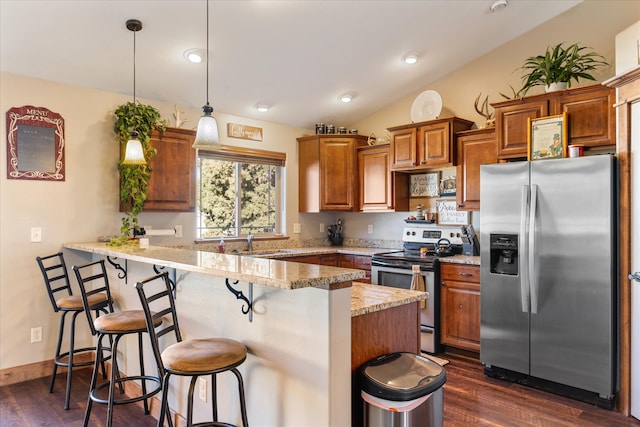 kitchen with kitchen peninsula, hanging light fixtures, dark hardwood / wood-style flooring, a kitchen bar, and stainless steel appliances