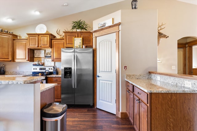 kitchen with kitchen peninsula, light stone countertops, vaulted ceiling, appliances with stainless steel finishes, and dark hardwood / wood-style flooring