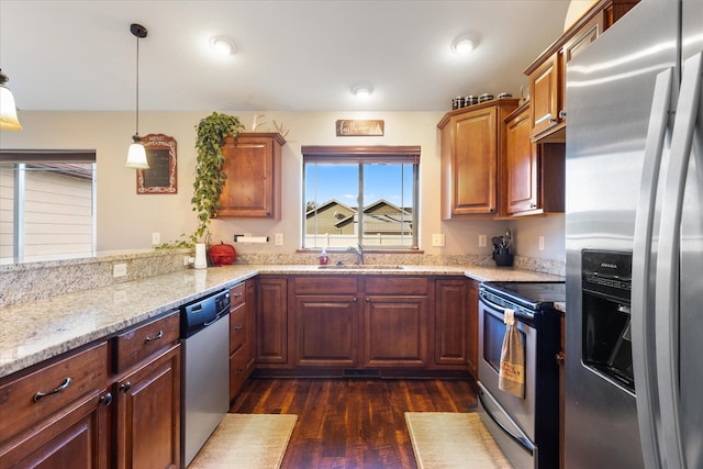 kitchen with appliances with stainless steel finishes, sink, dark hardwood / wood-style flooring, pendant lighting, and light stone counters