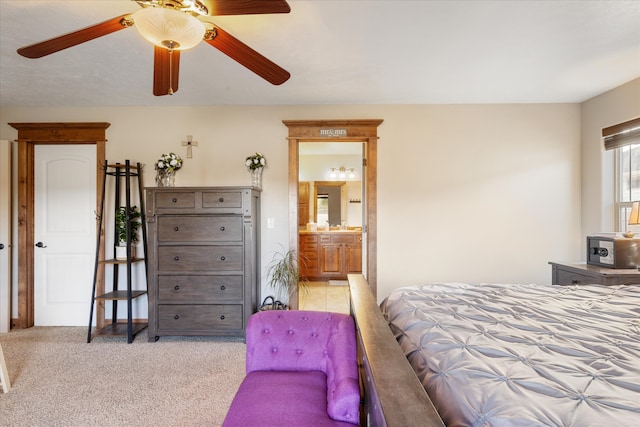 bedroom with ensuite bath, light colored carpet, and ceiling fan