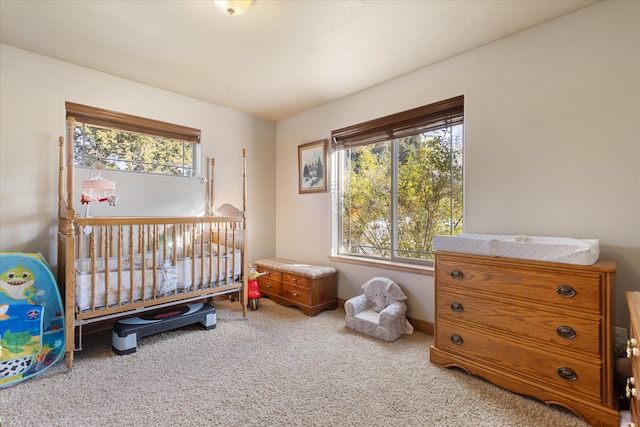 bedroom with multiple windows, carpet floors, and a crib