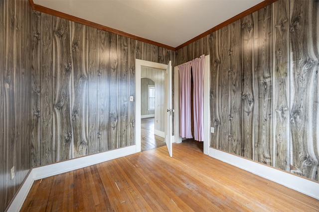 spare room featuring wooden walls, crown molding, and hardwood / wood-style flooring