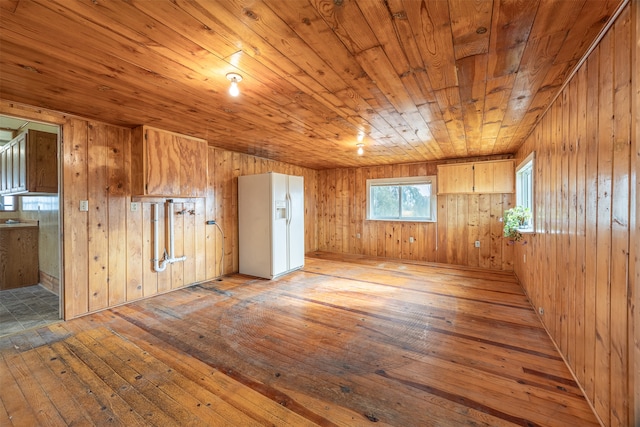 spare room with wooden walls, wood ceiling, and light wood-type flooring