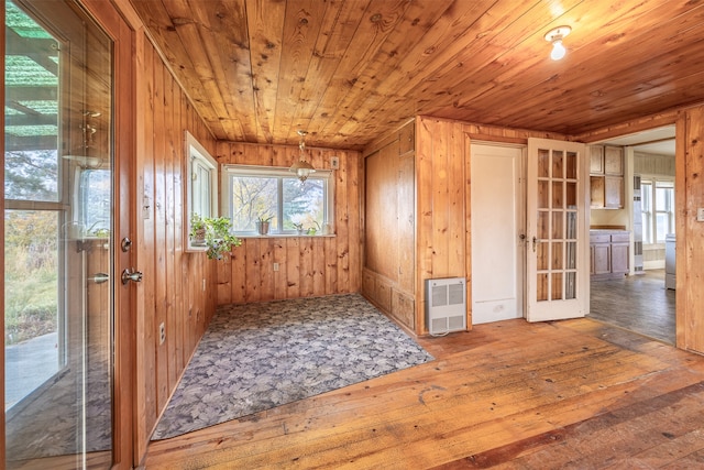 interior space featuring hardwood / wood-style floors, heating unit, wooden ceiling, and wooden walls