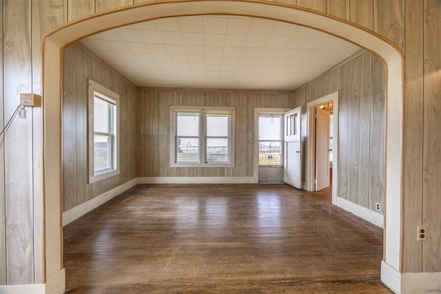 unfurnished room featuring dark wood-type flooring and wooden walls