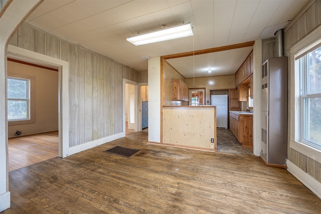 kitchen with sink, dark wood-type flooring, wooden walls, and white refrigerator