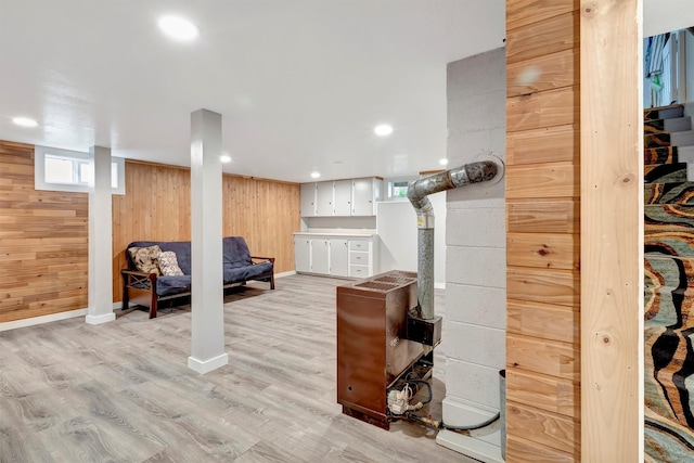 basement with light hardwood / wood-style flooring and wooden walls