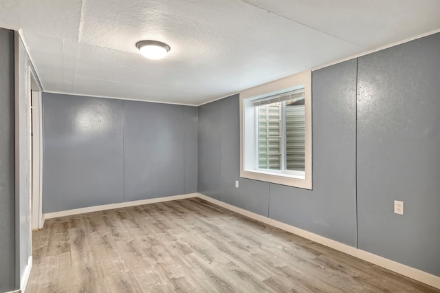 spare room with a textured ceiling and light wood-type flooring