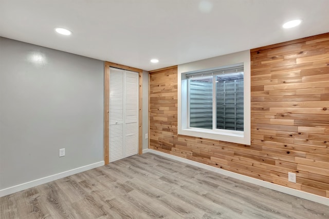 unfurnished bedroom with wood walls, a closet, and light hardwood / wood-style floors