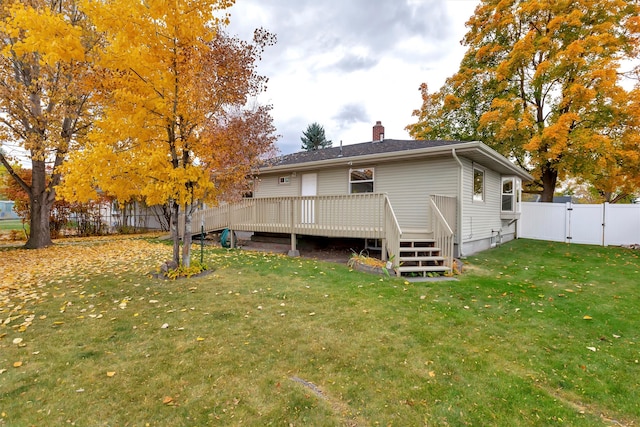 rear view of house featuring a lawn and a deck