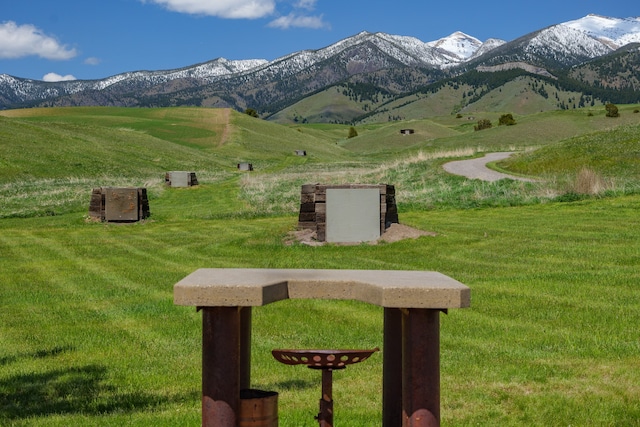 view of community with a mountain view, a lawn, and a rural view