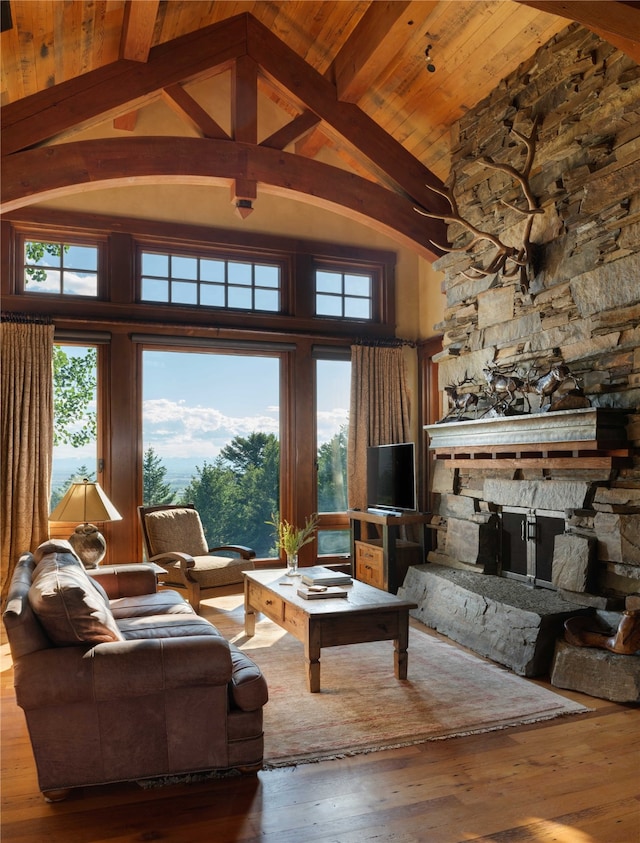 living room featuring beamed ceiling, hardwood / wood-style flooring, high vaulted ceiling, and a stone fireplace