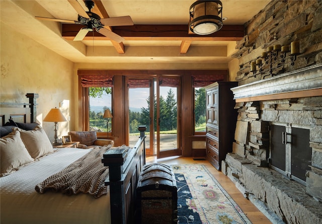 bedroom with beam ceiling, ceiling fan, access to outside, a fireplace, and light hardwood / wood-style floors