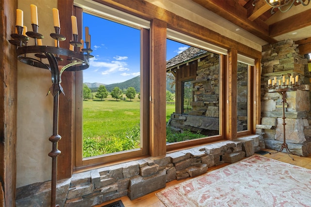 interior space with a mountain view, a notable chandelier, beamed ceiling, and hardwood / wood-style floors