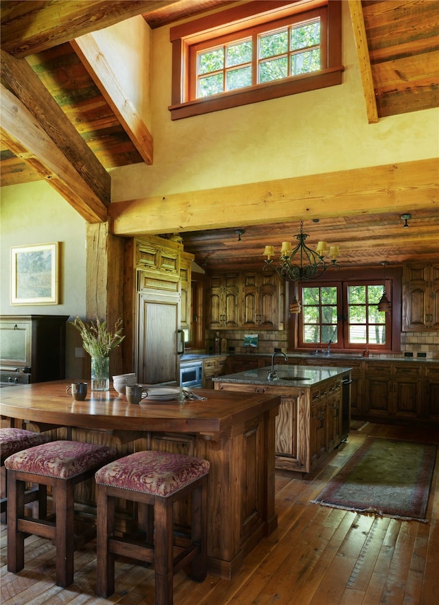 kitchen featuring dark hardwood / wood-style flooring, a chandelier, plenty of natural light, and a kitchen island with sink