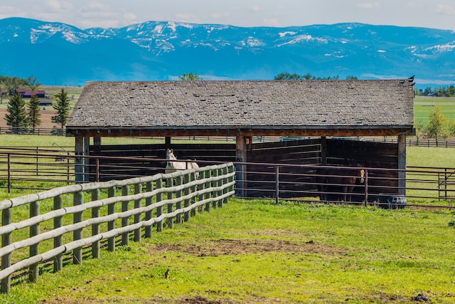 view of horse barn with a mountain view and a rural view