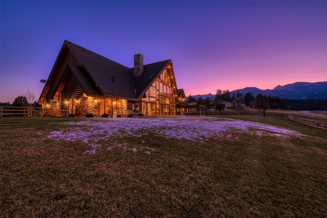 property exterior at dusk featuring a mountain view and a yard