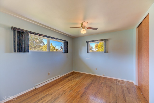 empty room featuring ceiling fan, baseboard heating, and light hardwood / wood-style flooring