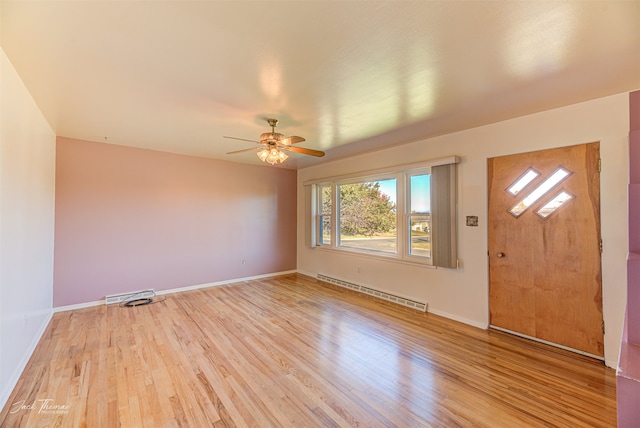 unfurnished living room featuring light wood-type flooring, baseboard heating, a healthy amount of sunlight, and ceiling fan with notable chandelier