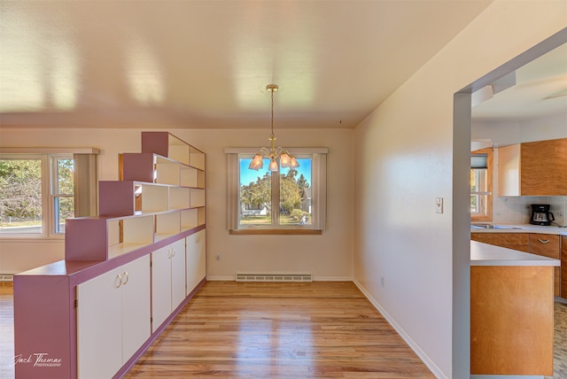 kitchen featuring white cabinetry, light wood-type flooring, ceiling fan with notable chandelier, and decorative light fixtures