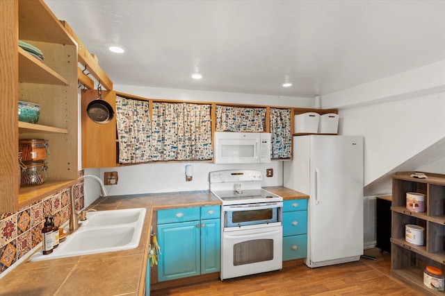 kitchen with tile countertops, light wood-type flooring, sink, blue cabinets, and white appliances