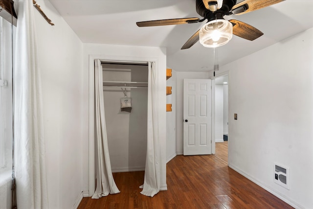 unfurnished bedroom with dark wood-type flooring, heating unit, a closet, and ceiling fan