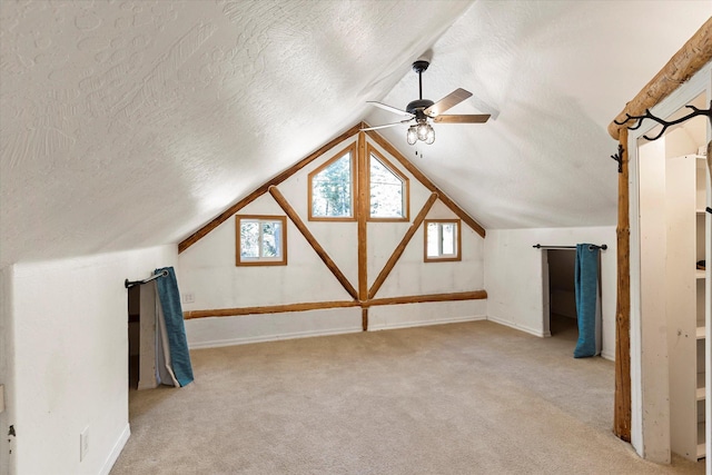 1424 Bierney Creek Rd, Lakeside, MT 59922 - additional living space with a textured ceiling, ceiling fan, light colored carpet, lofted ceiling, and baseboards