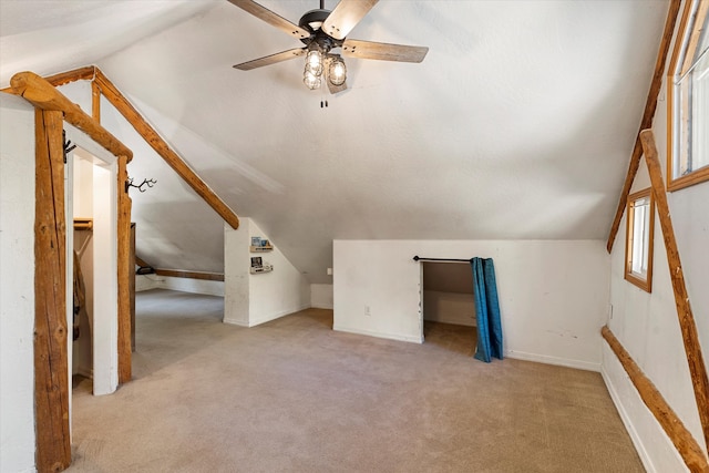 additional living space with light carpet, lofted ceiling, a wealth of natural light, and ceiling fan