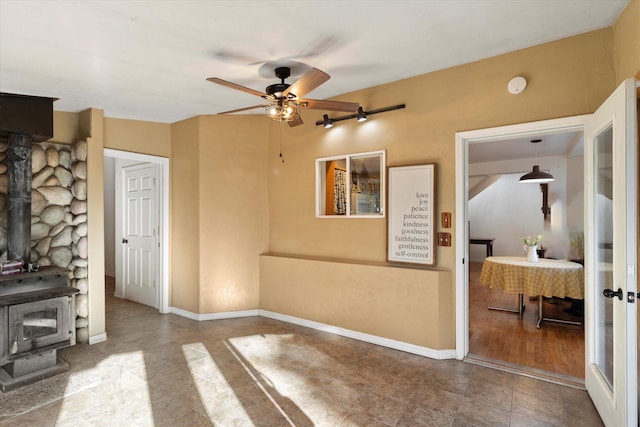 1424 Bierney Creek Rd, Lakeside, MT 59922 - unfurnished living room with a wood stove, ceiling fan, tile patterned flooring, and baseboards