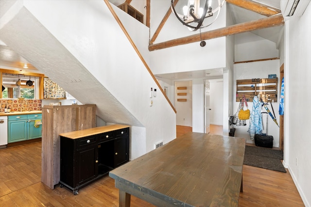 kitchen with a towering ceiling, dishwasher, light wood-type flooring, wooden counters, and a wall mounted AC