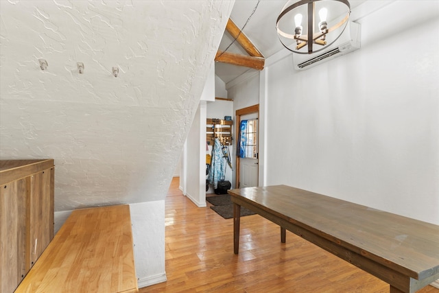 hall with a wall mounted AC, hardwood / wood-style flooring, a chandelier, and vaulted ceiling