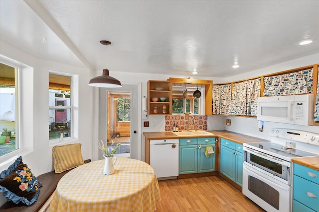 kitchen featuring decorative backsplash, hanging light fixtures, white appliances, sink, and light hardwood / wood-style floors