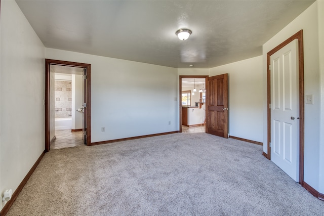 unfurnished bedroom with ensuite bathroom and light carpet