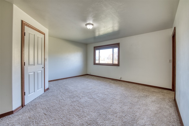 unfurnished room with light colored carpet and a textured ceiling