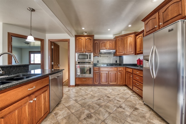 kitchen featuring dark stone counters, backsplash, appliances with stainless steel finishes, hanging light fixtures, and sink