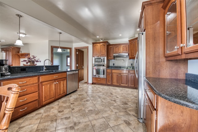 kitchen featuring dark stone counters, sink, appliances with stainless steel finishes, and decorative light fixtures