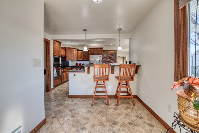 kitchen with pendant lighting, appliances with stainless steel finishes, a breakfast bar, and kitchen peninsula