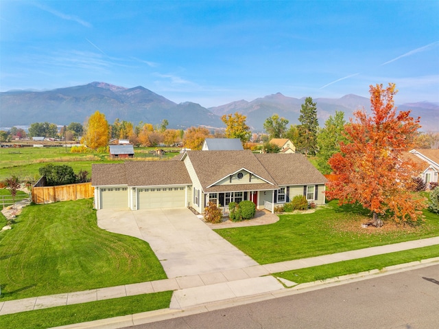 ranch-style home featuring a mountain view, a front yard, and a garage