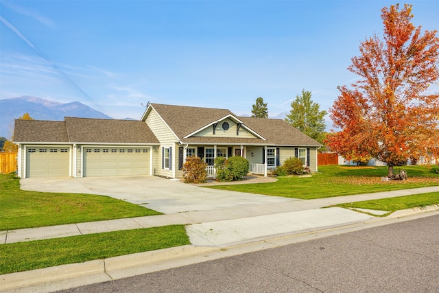 ranch-style home with a porch, a garage, a mountain view, and a front lawn