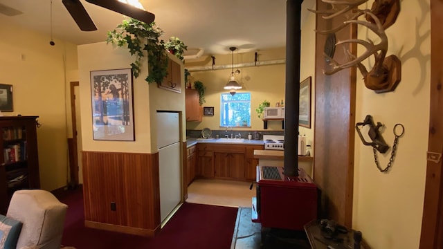 132 Little Mountain Rd, Whitefish, MT 59937 - kitchen featuring white microwave, a sink, a ceiling fan, brown cabinets, and a wood stove