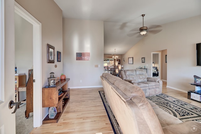 living room featuring light hardwood / wood-style floors, high vaulted ceiling, and ceiling fan with notable chandelier