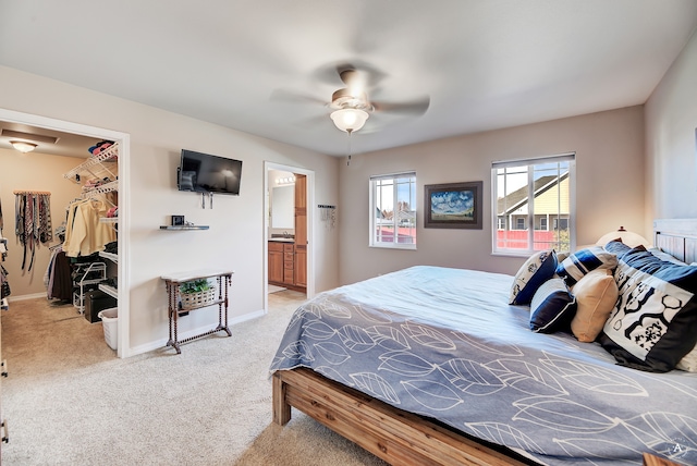 bedroom with ceiling fan, a spacious closet, ensuite bathroom, a closet, and light colored carpet