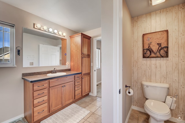 bathroom with toilet, wooden walls, vanity, and tile patterned flooring