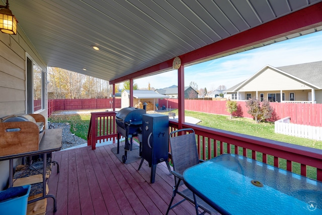 wooden terrace with a yard, a storage shed, and a grill