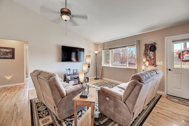 living room with a healthy amount of sunlight, ceiling fan, light wood-type flooring, and vaulted ceiling