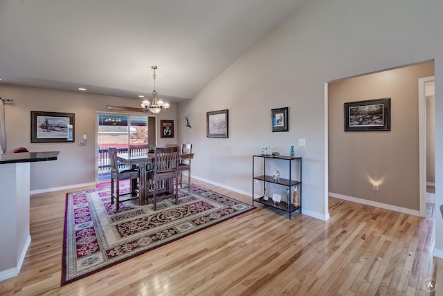 dining area with light hardwood / wood-style flooring, high vaulted ceiling, and an inviting chandelier