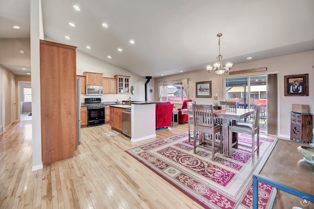 kitchen with a center island, pendant lighting, light wood-type flooring, a chandelier, and appliances with stainless steel finishes